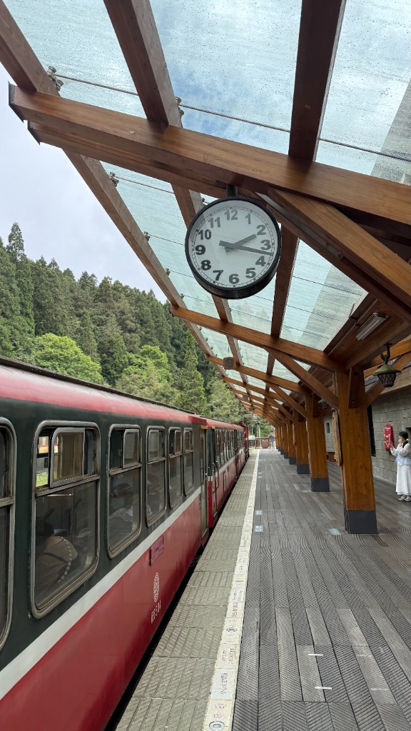Quai de la gare d'Alishan avec le train rouge et une horloge suspendue sous la verrière en bois